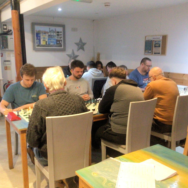 Two teams of players in a cafe playing chess.